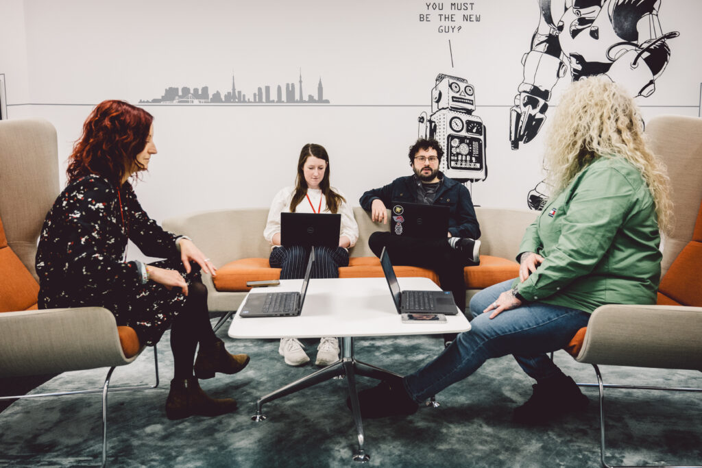 Four people sat round a table with laptops