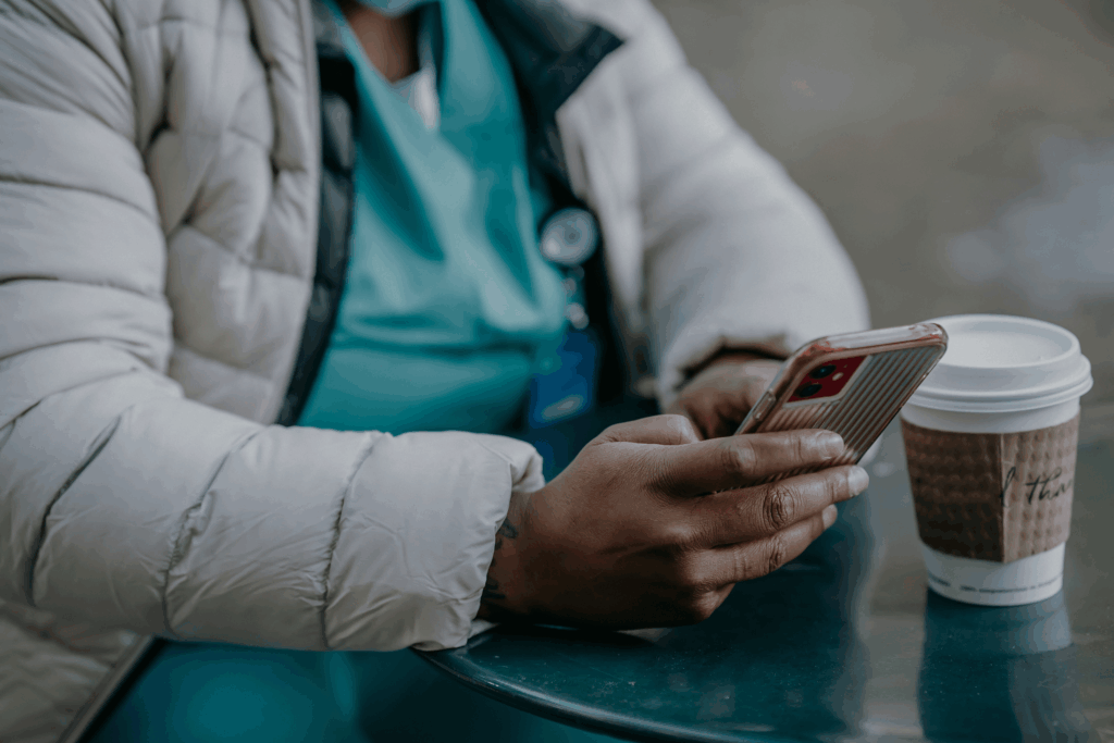 Nurse sat with a coffee holding a mobile phone