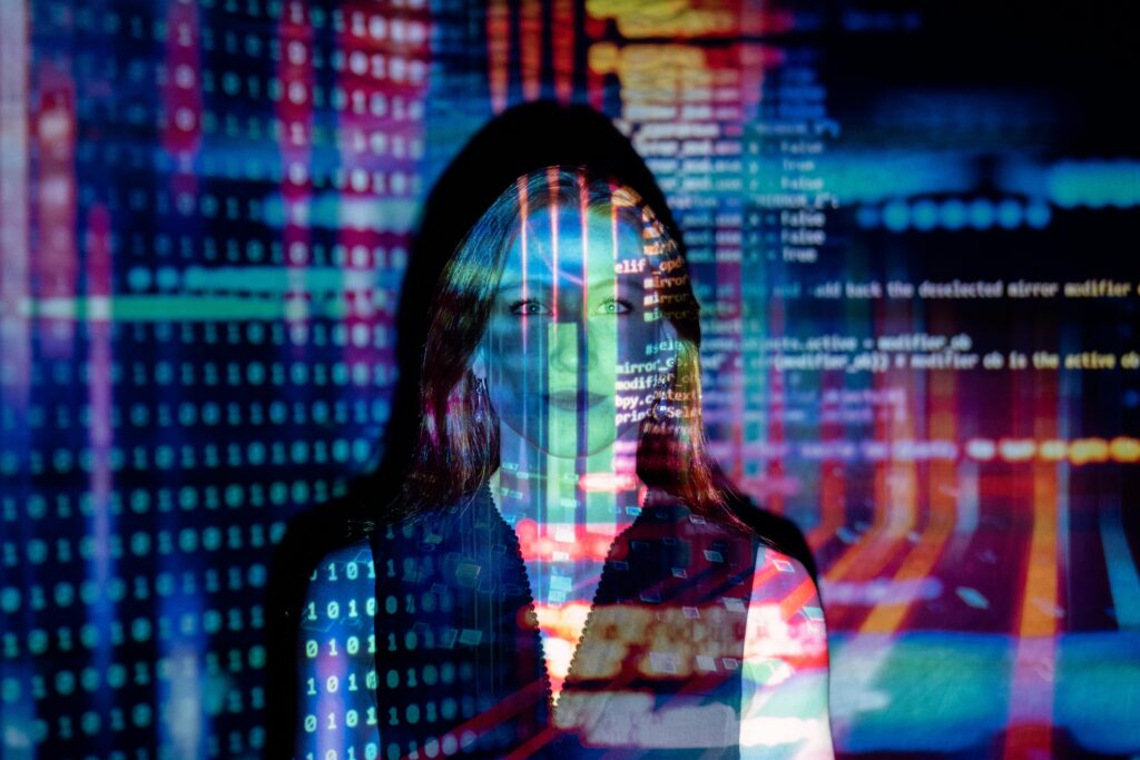 Woman stood with code projected onto her face, body and background