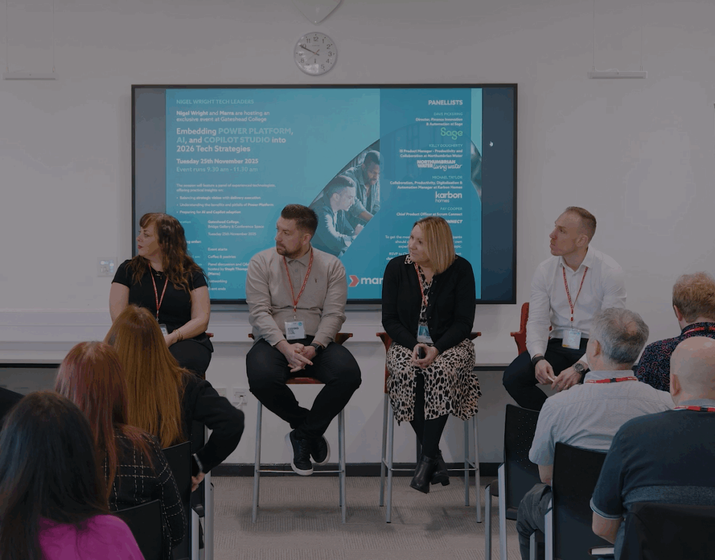Four people sat on stools at the front of a room looking to the left