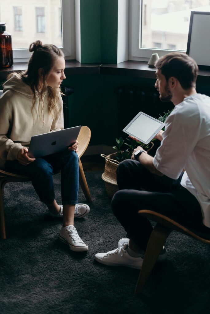 a man and woman sat down looking at information on an ipad
