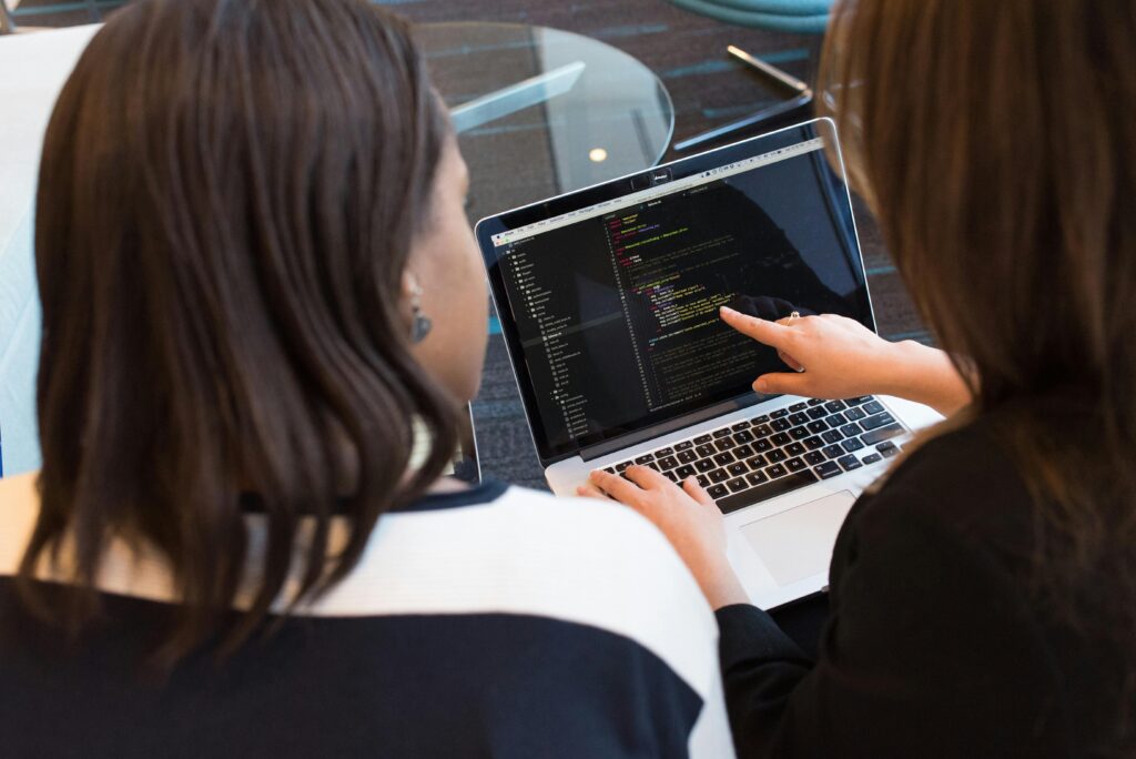 Shot of two women looking at code on a laptop screen