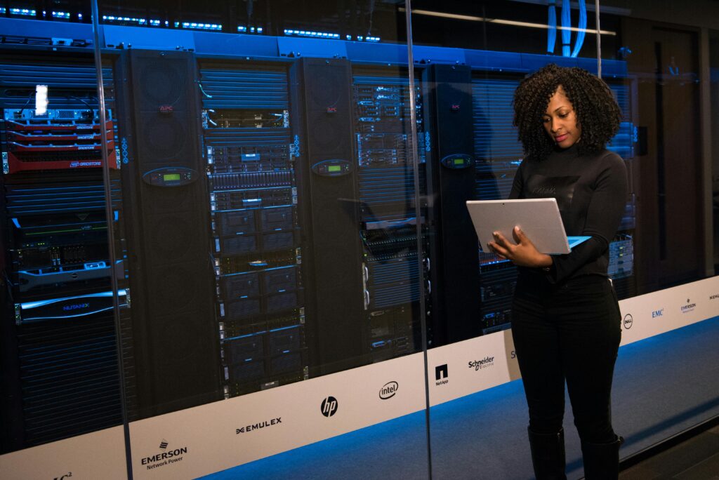 Woman stood with an open laptop next to a data centre
