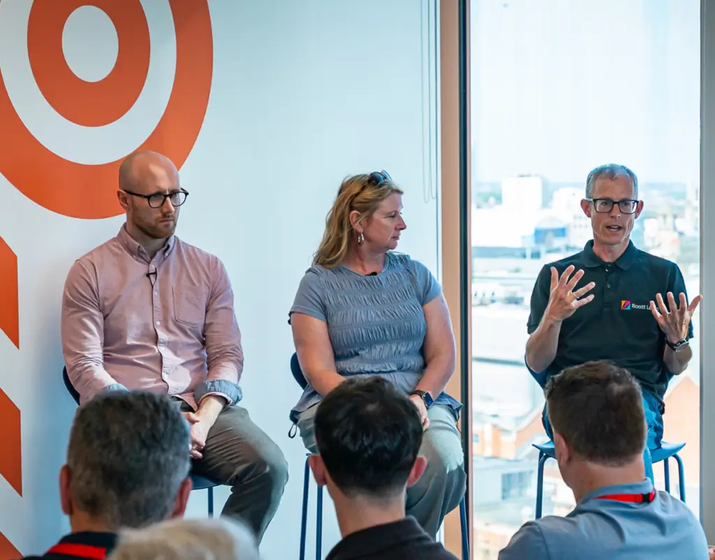 Four people taking part in a panel discussion as part of an AI event in front of a watching audience.